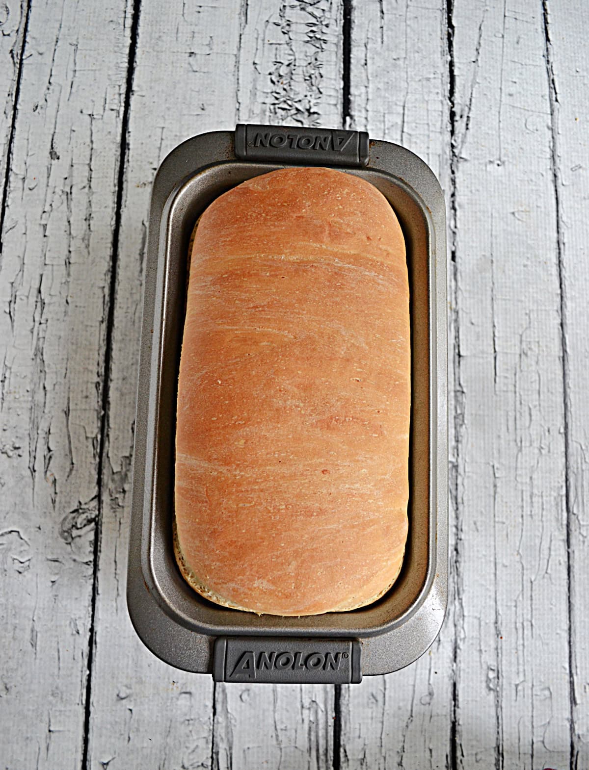 A loaf of golden brown bread in a loaf pan.