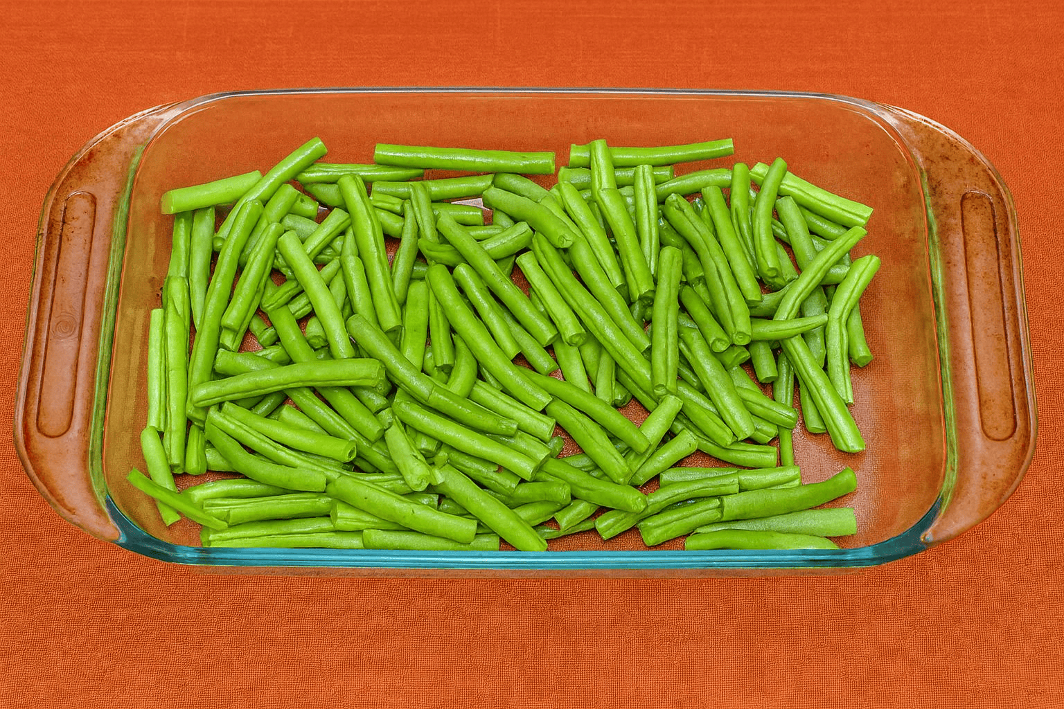 A baking dish with green beans in it.