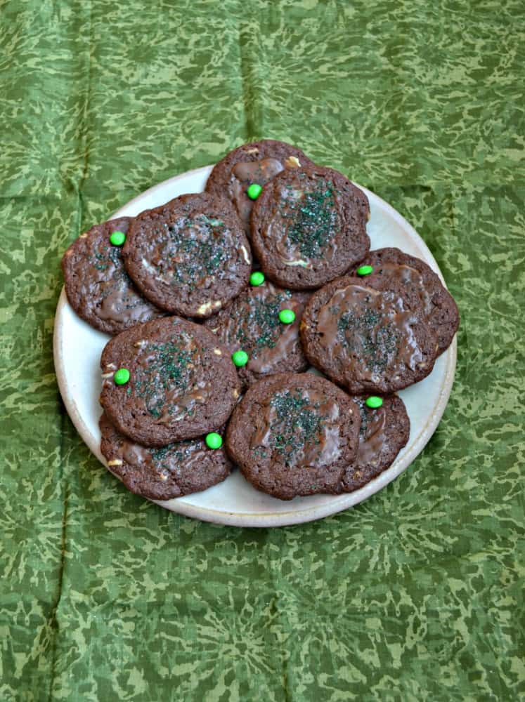 A plate of chocolate mint cookies with green M&M's on top. 