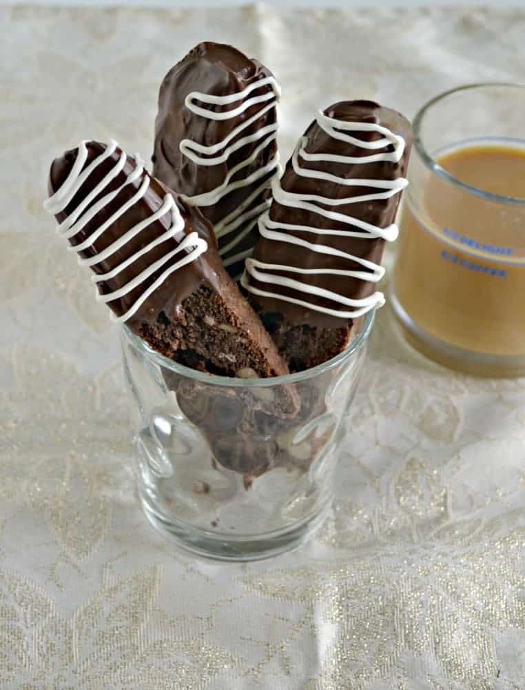A cup with three chocolate dipped biscotti in it. 