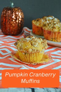 A close up of a pumpkin muffin with a plate of muffins in the background.