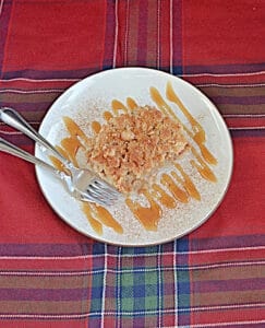 An overhead view of a plate with a pear pie bar drizzled with caramel sauce and two forks on the plate.