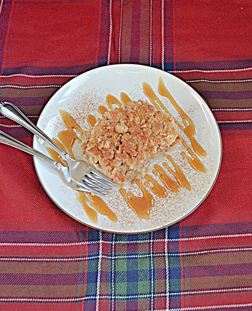 An overhead view of a plate with a pear pie bar drizzled with caramel sauce and two forks on the plate. 