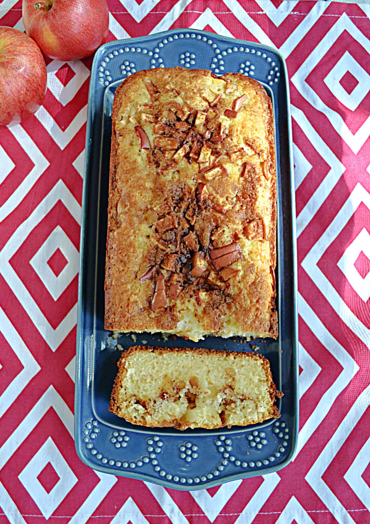 A platter with a loaf of bread with a slice cut off.