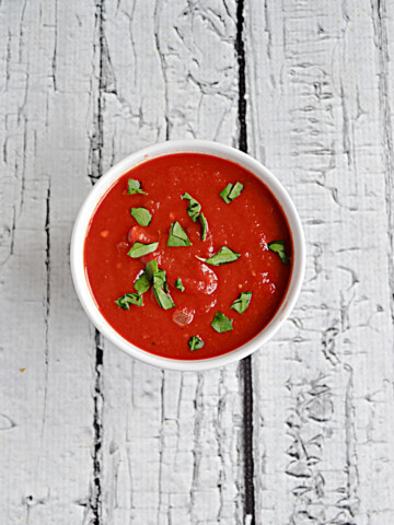 A top view of a bowl of tomato sauce with parsley on top.
