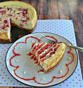 Grab a fork and dig into this Strawberry Swirl Cheesecake drizzled in white chocolate and strawberry sauce.