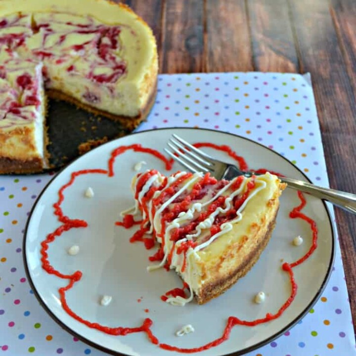 Grab a fork and dig into this Strawberry Swirl Cheesecake drizzled in white chocolate and strawberry sauce.
