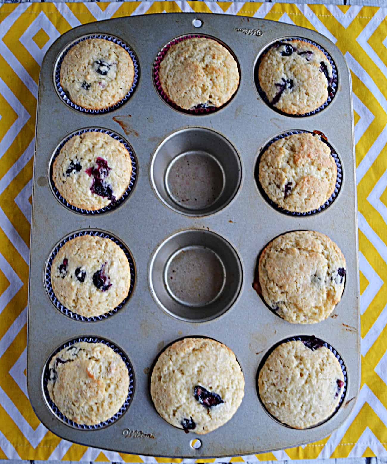 A muffin tin of baked blueberry muffins.