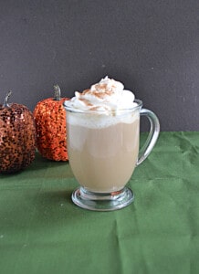 A close up of a Pumpkin Latte with whipped cream and caramel sauce.