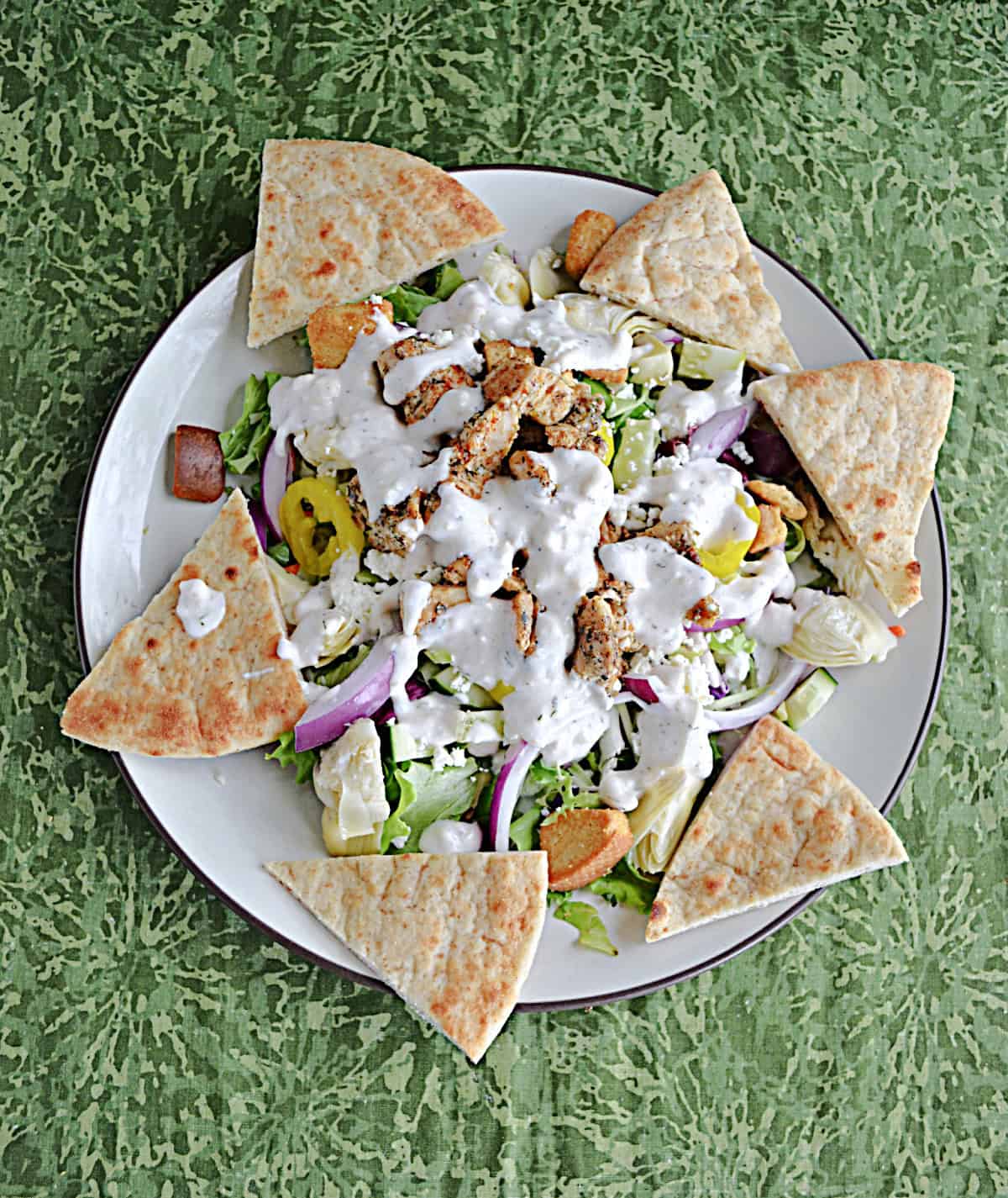A plate of salad with pita bread and dressing.