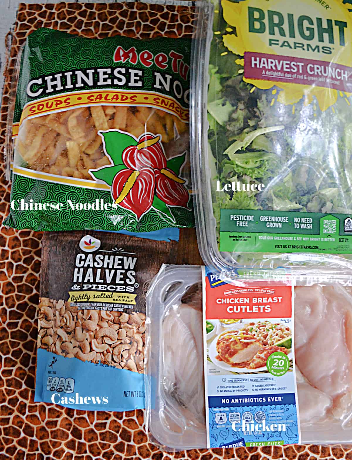Asian crunchy noodles, a bag of salad mix, a package of chicken, and a bag of cashews.