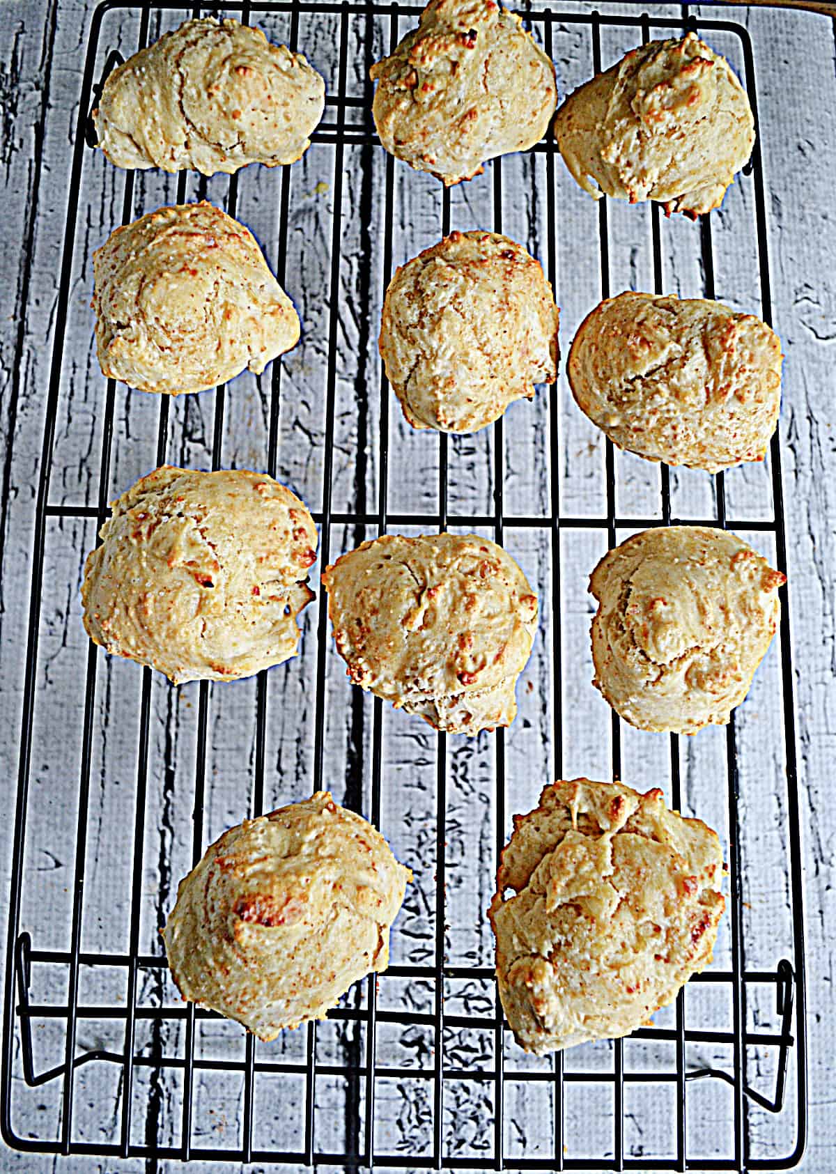 A cooling rack with a dozen biscuits on it. 