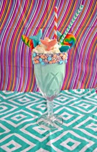 Kids are going to love these Mermaid Milkshakes topped with candy mermaid tails, rainbow lollipops, and shark gummies.