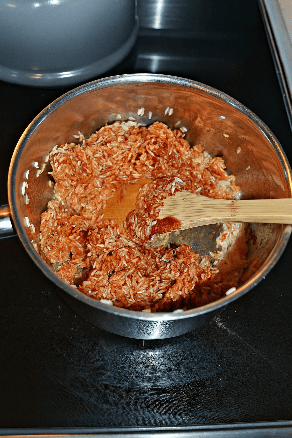A pot of red rice with a spoon in it.
