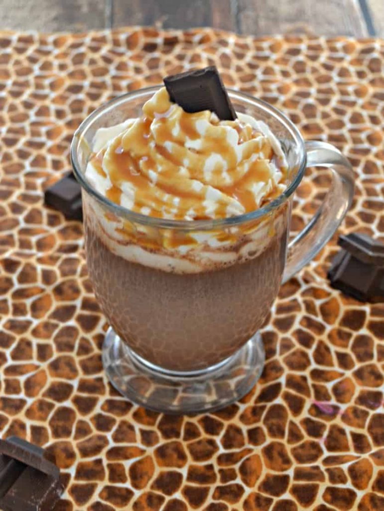A mug of hot cocoa with whipped cream, caramel, and chocolate on top. 