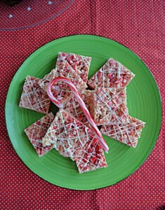 A plate of Rice Krispies squares with a candy cane on top.