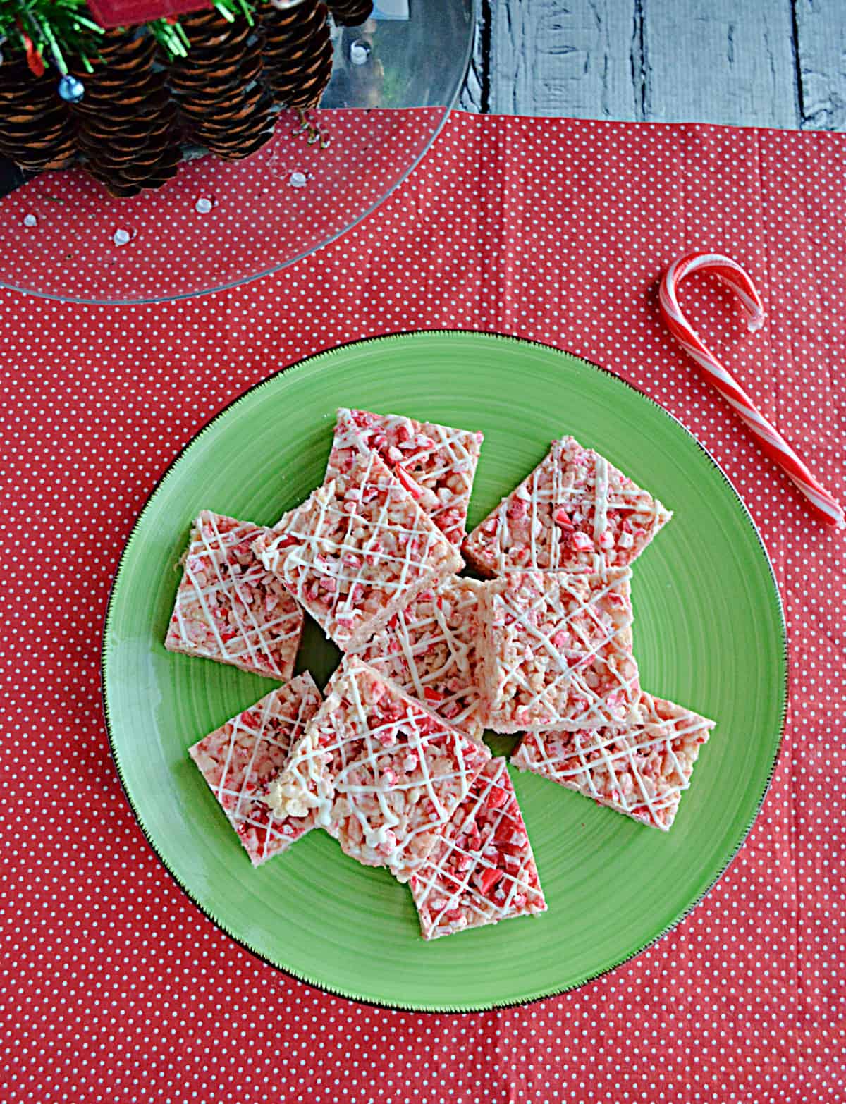 A plate of Candy Cane Rice Krispies Treats with a candy cane beside the plate.