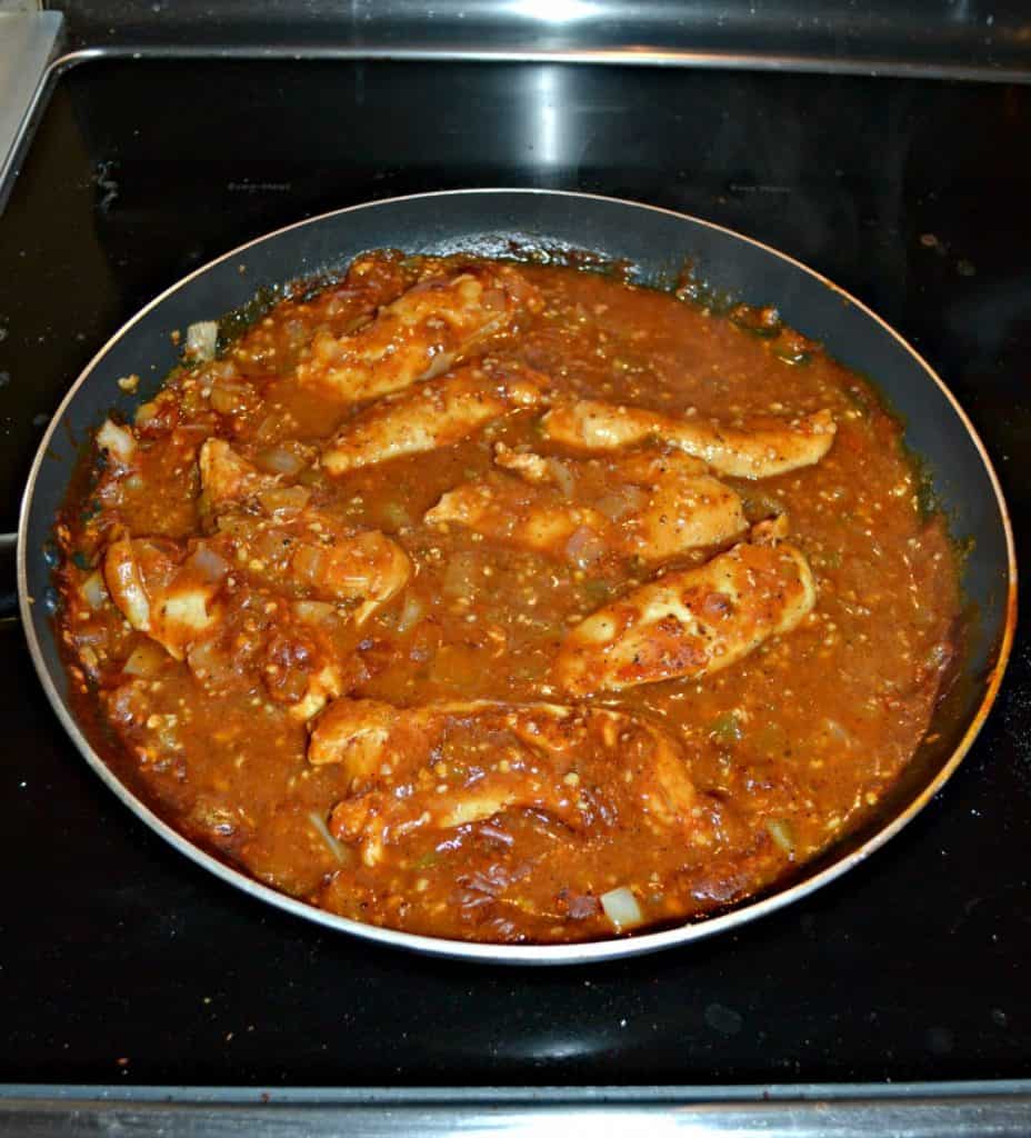 Chicken simmering in enchilada sauce
