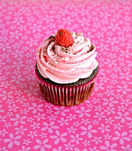 A single raspberry mocha cupcake topped with raspberries