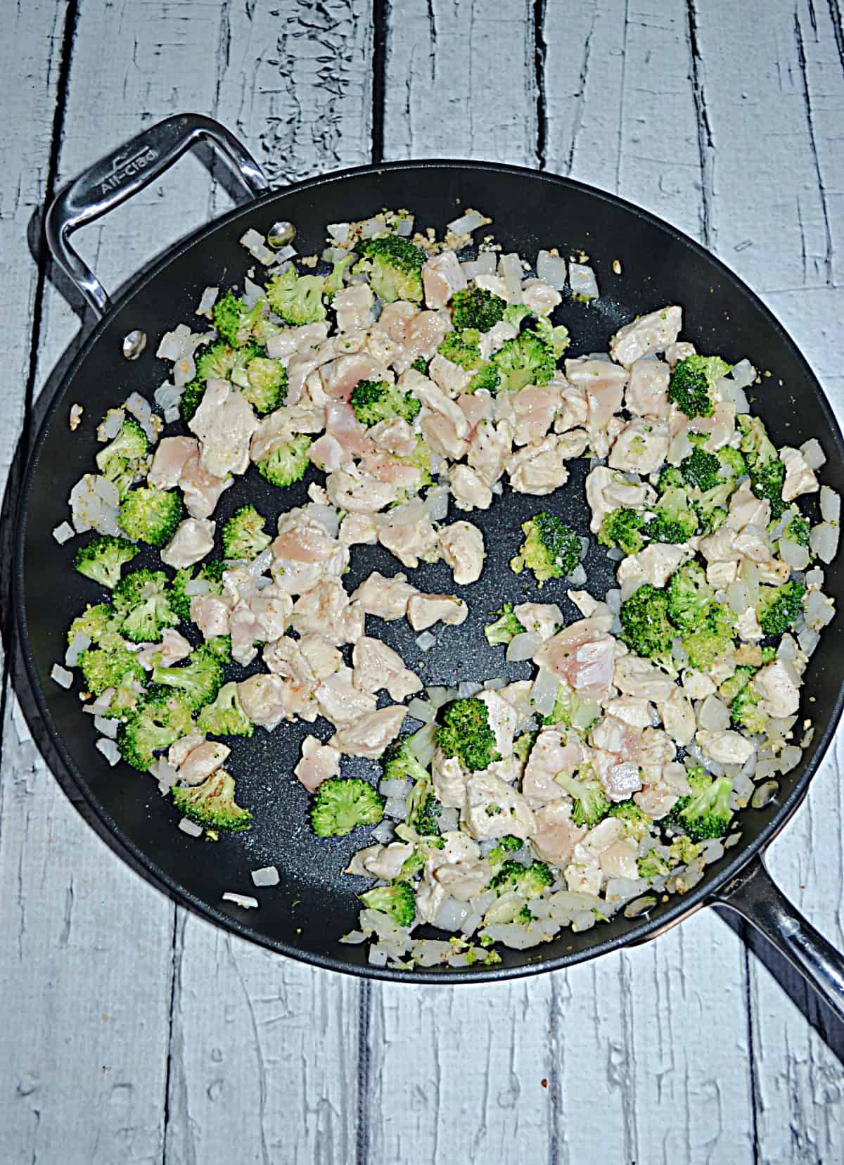A skillet with peppers, chicken, and onions in it.