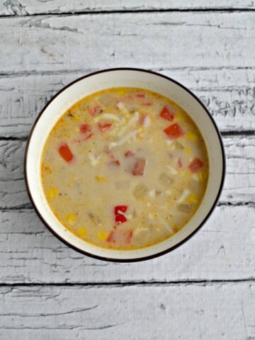 A bowl of Corn and Potato Chowder on a wooden backdrop.