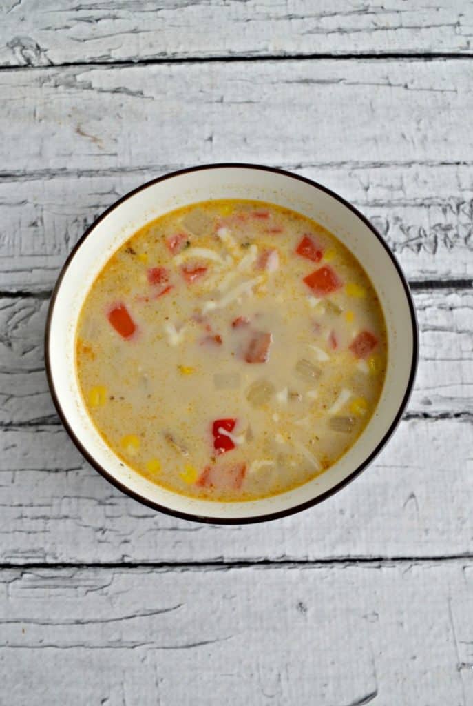 A bowl of Corn and Potato Chowder on a wooden backdrop.