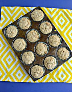 A muffin tin filled with hummingbird muffins sitting on a white and yellow placemat.