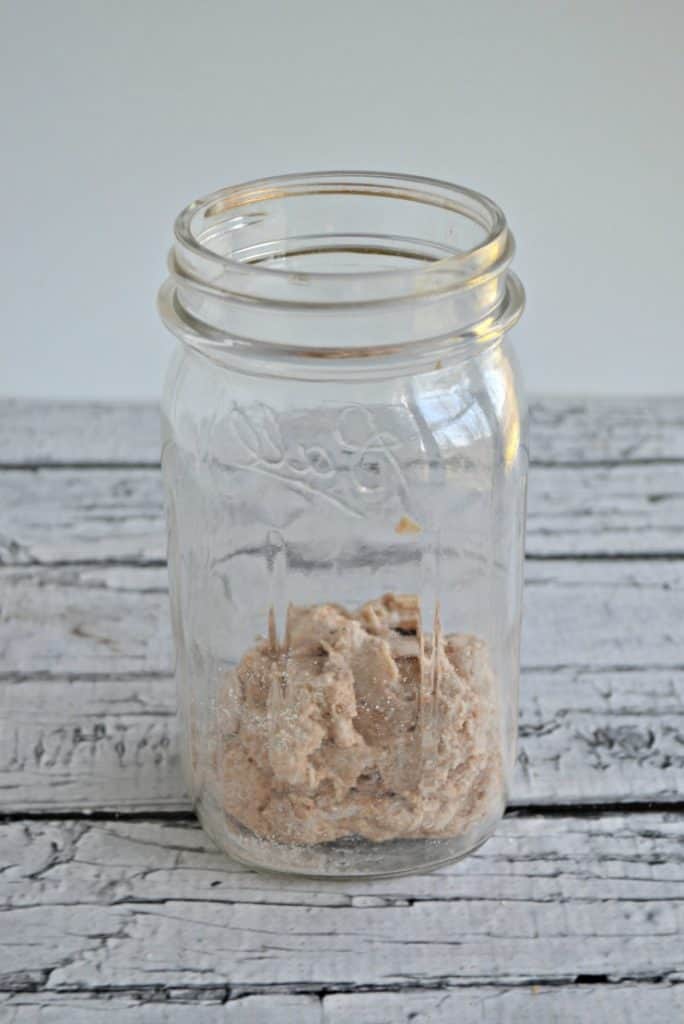 Glass jar with the beginning of water and flour mixture rolled in a ball.