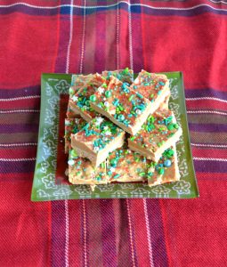 A pile of fudge on a green plate sitting on a plaid tablecloth