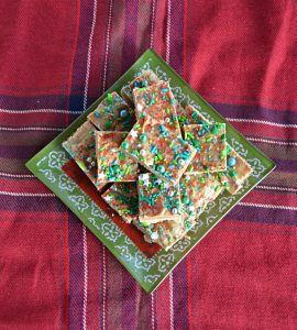 A pile of fudge on a green and red plate sitting on a red plaid tablecloth.