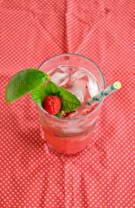 Top view of Raspberry Mojito in a glass filled with ice and garnished with a raspberry and mint sprig.