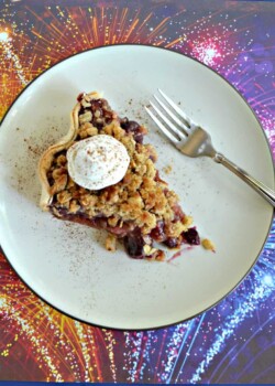 A top view of a plate topped with a slice of pie with a scoop of whipped cream on top with a fork sitting next to it sitting on a firework background.
