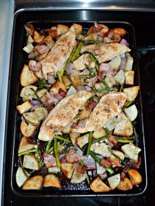 A sheet pan scattered with potatoes, sourdough croutons, chicken breasts, and fresh rosemary.