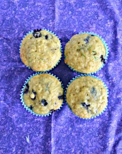 Top view of four blueberry muffins on a purple background.