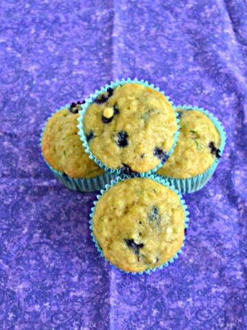 Top view of three muffins facing up with one muffin on top of the other three all on a purple background.