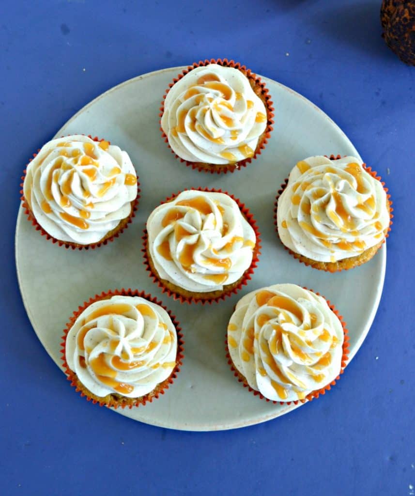 Top view of six cupcakes topped with frosting and drizzled with caramel sauce.