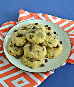 A plate piled high with chocolate chip cookies set on an orange napkin.