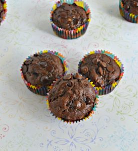 Three chocolate muffins with one in the background all on a white background.