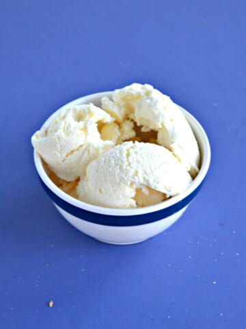 Three scoops of ice cream in a white bowl on a blue background.