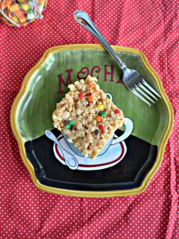 A plate with a single Rice Kripsies Treat on it with a fork in the upper left on a red background.