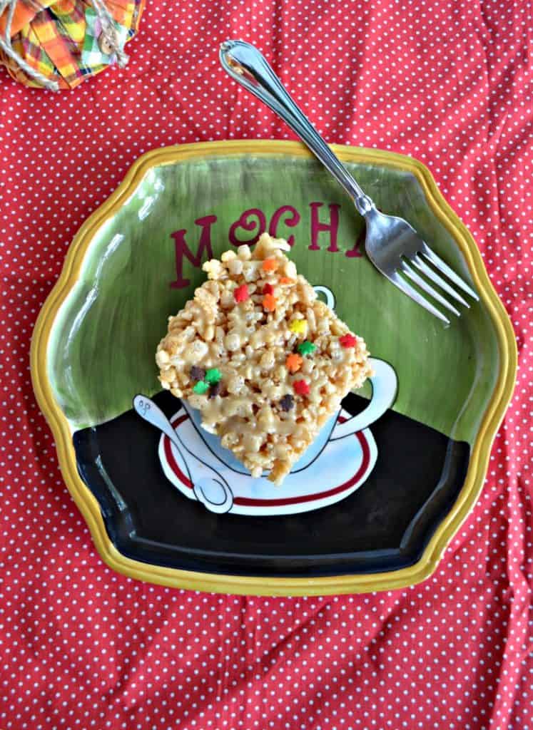 A plate with a single Rice Kripsies Treat on it with a fork in the upper left on a red background.