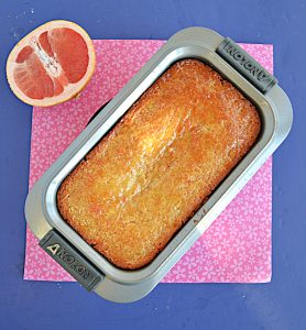 Grapefruit cake in a loaf pan with half a grapefruit in the background.