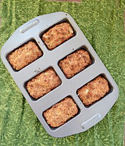 A mini loaf baking pan filled with 6 mini loaves of pear ginger cakes.