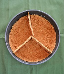 A springform pan with a graham cracker crust and graham cracker dividers.