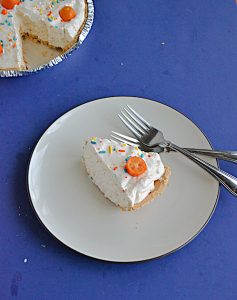 A plate with a slice of No Bake Kumquat Pie on it with two forks and the whole pie minus one slice peaking out from the corner.