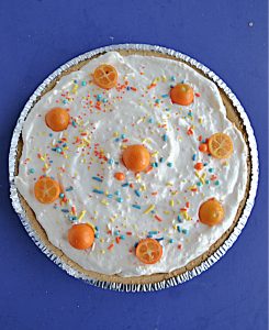 No Bake Kumquat Pie is topped with whipped cream and little kumquats and sprinkles.