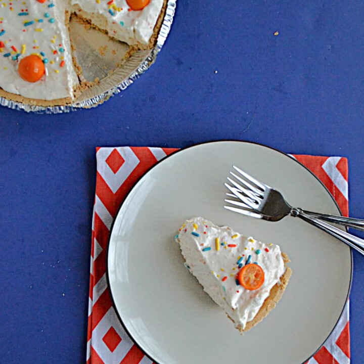 A slice of No Bake Kumquat Pie with a kumquat on top and the pie with a slice cut out of it in the upper left hand corner.