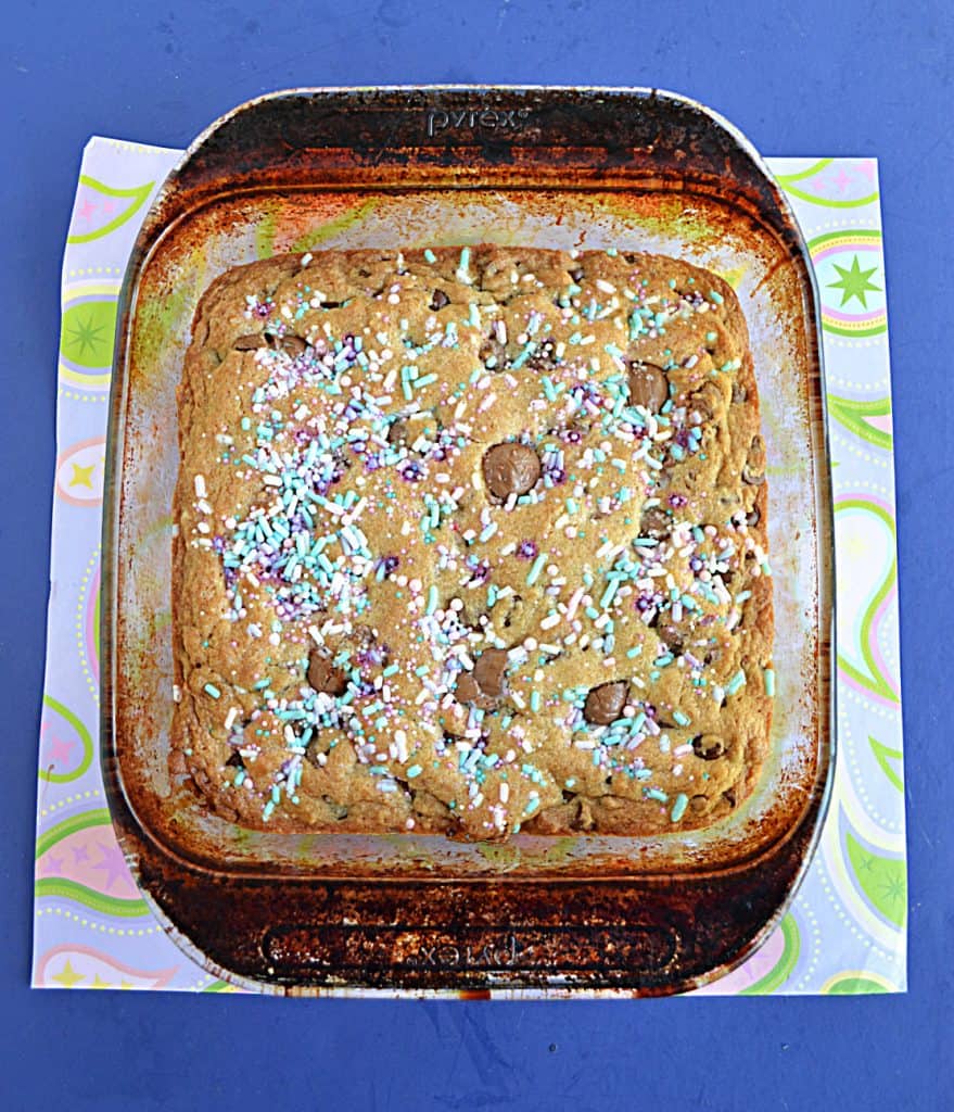 A pan of blondies studded with chocolate chips and Cadbury mini creme eggs then topped with pastel sprinkles. 