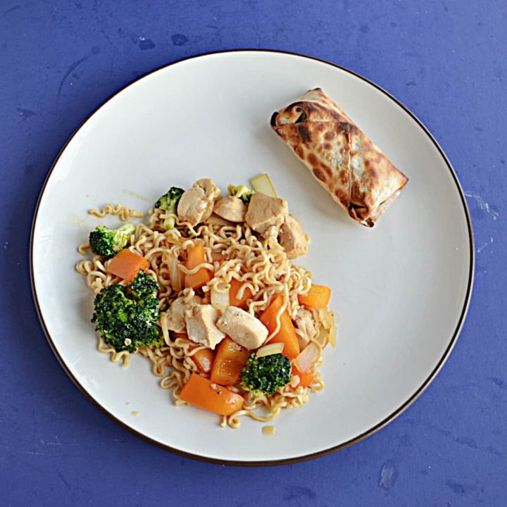 A plate with a large serving of chicken, vegetable, and ramen noodle stir fry with an egg roll on the side.