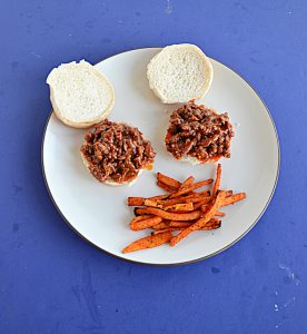 A plate with 2 Korean BBQ Sloppy Joes with a side of sweet potato fries.